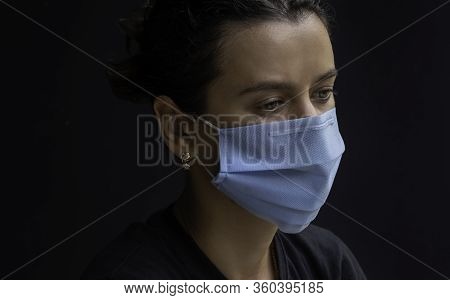 Worried Young Woman Wearing Medical Face Mask, Studio Portrait. Woman Wearing Face Mask During Coron
