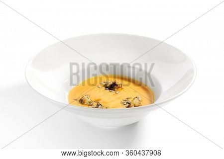 Pumpkin soup in white bowl. Served main course close up. Vegetable cream soup decorated with seeds. Restaurant food portion, main course. Vegetarian supper. Dinner, gourmet meal in plate