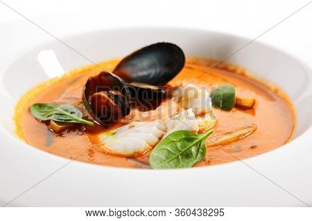 Bouillabaisse in white bowl. Served main course close up. French seafood, soup with fish and mussels. Restaurant food portion, main course. France cuisine. Dinner, gourmet meal in plate