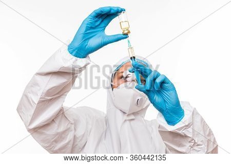 Female Doctor In A Protective White Suit With A Syringe In His Hands And Blue Rubber Gloves Stands I