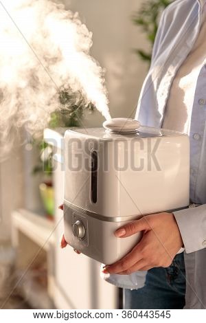 Woman Holding In Her Hands Working Aroma Oil Humidifier In Sunny Room. Humidification Of Air In The 