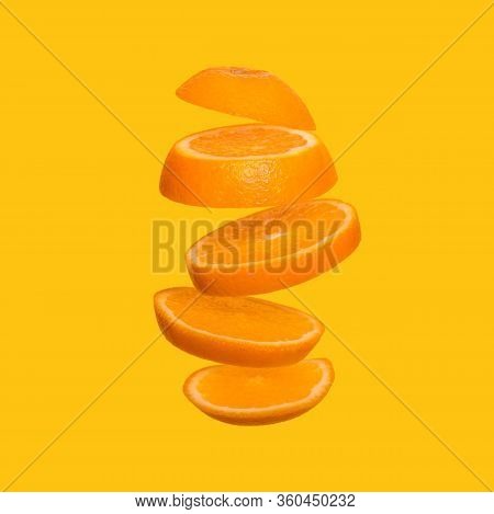 Creative Concept With Flying Orange. Sliced Orange On Yellow Background. Levity Fruit Floating In Th