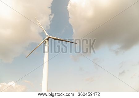 Wind Turbine Against A Cloudy Blue Sky