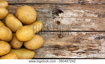 Raw Uncooked Organic Potatoes Over Natural Weathered Wooden Boards. Top View. Copy Space.