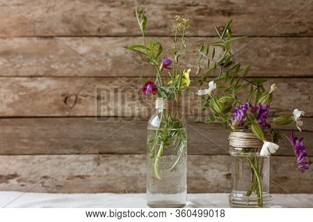 Meadow Natural Wildflowers Bouquets In Glass Jars And Bottles On Wooden Rustic Background. Herbal Me