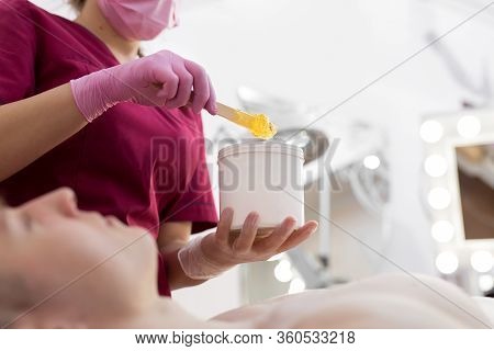 Cosmetician Takes The Sugar Paste From The Jar. Shugaring. Sugar Paste Out Of The Container With A S