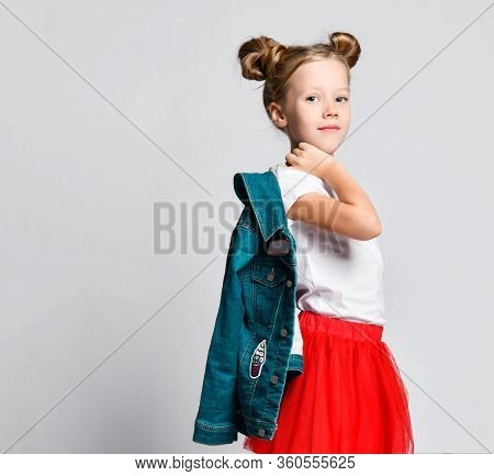 Smiling Blonde Kid Girl With Funny Buns Hairstyle In Red Skirt And White T-shirt Walk Away With Deni
