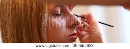 Close-up Of Makeup Artist Painting Arrows On Clients Face. Macro Shot Of Young Blonde Woman Visiting