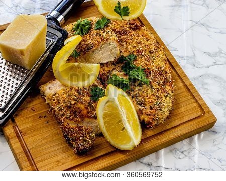 Itailain Bread Chicken With Fresh Lemon On A Wooden Cutting Board. Calgary, Alberta, Canada