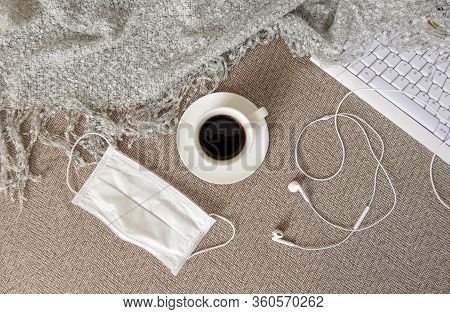 A Cup Of Coffee, A Keyboard, A Headphones, Plaid And A Medical Mask Are On The Sofa. Self-isolation,
