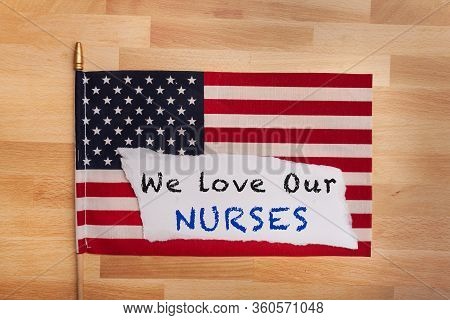 We Love Our Nurses Message Note Laying On An American Prideful Flag Flat Lay On Wooden Background