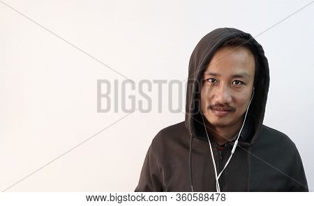 A Northeast Indian Asian Man In A Hoodie And Earphones Looking At The Camera And Isolated In White B
