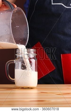 Milkshake Making On Wooden Table Closeup. Process Of Topping And Decorating Milkshake. Desset With C