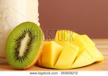 Mango And Kiwi Closeup On Wooden Table. Healthy Vegan Breakfast Of Raw Fruits. Closeup Of Sliced Fre