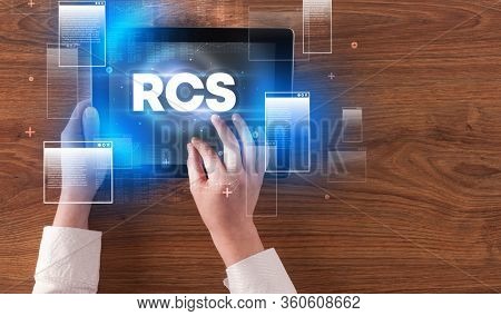 Close-up of a hand holding tablet with RCS abbreviation, modern technology concept
