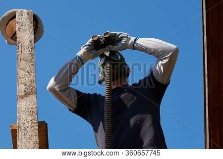 Man Looking Through Binoculars In A Tower, Wearing A Protection Face Mask, In Coronavirus Covid-19 P