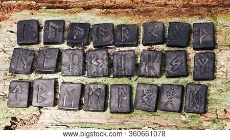 24 Norse Runes Stones On Old Wood Background. Close Up.