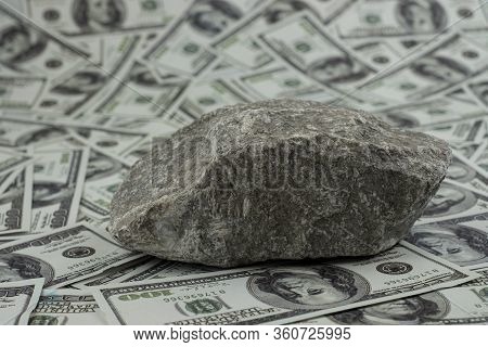 Stone On A Group Of Money Stack Of 100 Us Dollars Banknotes A Lot Of The Background