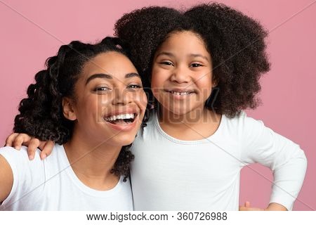 Capturing Happy Moments. Happy Black Mom And Little Daughter Taking Selfie, Posing Over Pink Backgro