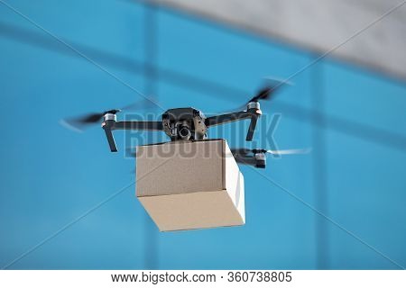 Drone For Air Delivery. Cardboard Package Shipment By Helicopter Drone Through The City While Quaran