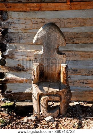 Rustic Wooden Chair Carved From Log Is The The Shape Of An Arrowhead.  The Letter C Sits Under The S