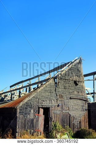 Barely A Shell Remains Of This Wooden Barn With Red Door.  Roof Has Caved In And Red Door Has Faded.