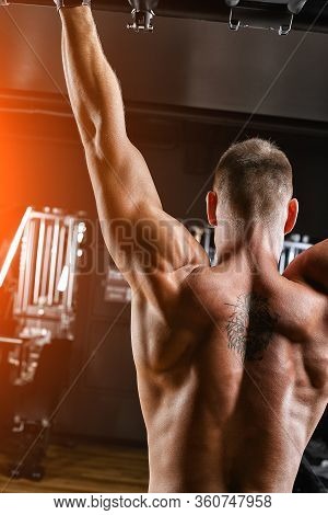 The Athlete Does A Pull-up On The Horizontal Bar. A Man In Great Shape Is Doing Pull-ups On The Hori