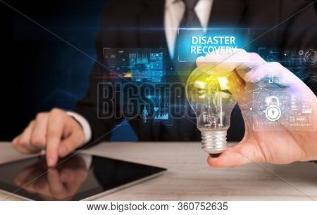 Businessman holding lightbulb with DISASTER RECOVERY inscription, online security idea concept