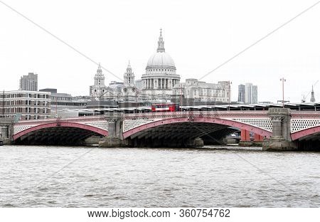 Iconic Red British Bus On Blackfriars Bridge With St Paul`s Cathedral And London Skyline In The Back