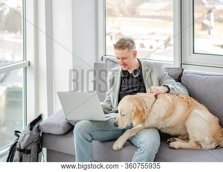 Businessman teleworking on laptop next to cute dog