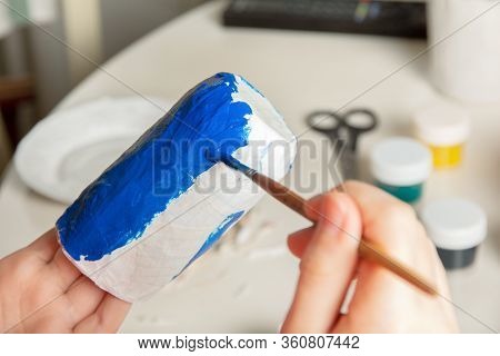 Making Utensils From Paper Mache. The Child Paints With A Brush A Blank Of Paper In The Shape Of A G