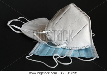 white KN95 or N95 mask with antiviral medical mask for protection against coronavirus on black backg
