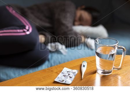 Woman Feeling Sick And Have Cramps Lying On Sofa And Have Some Medicamentation On Table