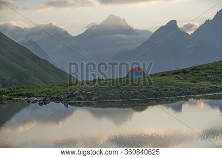 Tourist Tent In Mountains. Lake In Foreground.