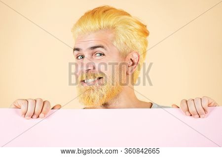 Happy Man Shows A Sheet Of Paper In The Camera On A Color Background. Young Man Holding Blank Sheet.