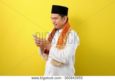 Happy Smiling Young Asian Muslim Man Wearing Moslim Clothes Holding Mobile Phone Look At Phone Scree
