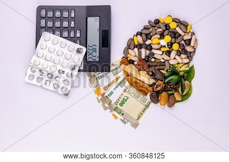 Top View Of Natural Medicines, Money, Calculator, Pills And Different Spices With Green Leaves On Wh