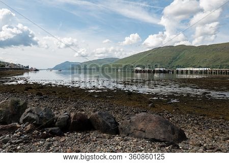 Loch Linnhe Pier In Fort William, Scotland At Low Tide With Boulders In The Foreground