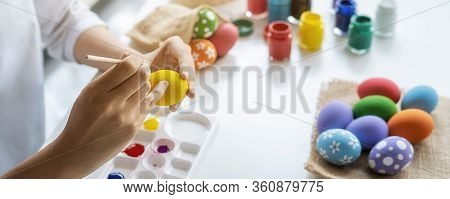 Happy Asian Woman Painting Eggs For Eastertime At Home. Family Preparing For Easter.