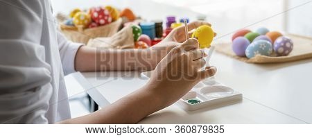Happy Asian Woman Painting Eggs For Eastertime At Home. Family Preparing For Easter.