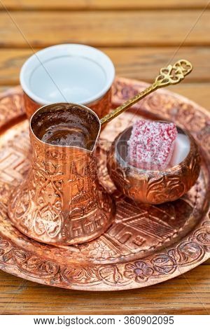 Traditional black bosnian coffee in beautiful copper cezve at wooden table. A complete Bosnian coffee set is called a kahveni takum