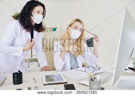 Young Serious Medical Laborary Workers Reading Document With Virus Spead Preventitive Measures