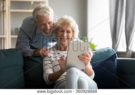 Happy Older Couple Using Computer Tablet Together At Home
