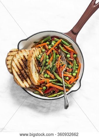 Green Beans, Sweet Peppers, Carrots, Onions, Green Peas Stir Fry In A Pan On A Light Background, Top