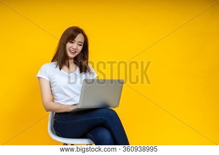 Young Asian Woman Teen Smiling Sitting On Chair Wearing T-shirt Using Laptop Computer For Work From 