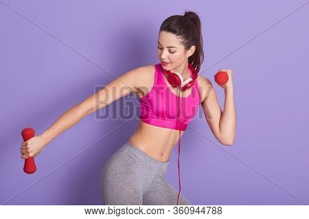 Picture Of Sporty Good Looking Cute Fitness Trainer Doing Physical Exercises, Holding Red Dumbbells,
