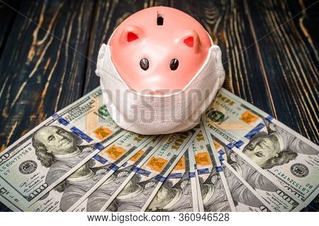 Piggy Bank In A Mask On A Background Of American Currency.the Concept Of Coronavrius Epidemic