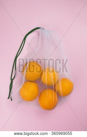 Oranges In Mesh Bag Flat Lay On Pink Background