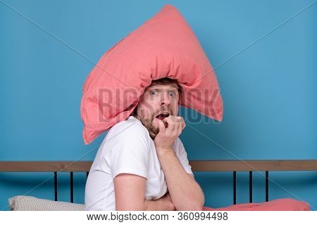 Cauacsian Young Man With Pillow On Head In Bed Being Afraid