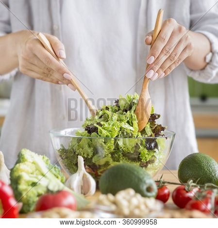 Woman Cooking Healthy Food In The Kitchen And Mixing Fresh Salad In Glass Bowl